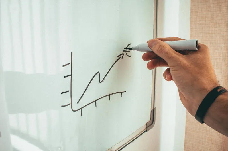 A person drawing a strategy diagram on a whiteboard, mapping out a step-by-step plan