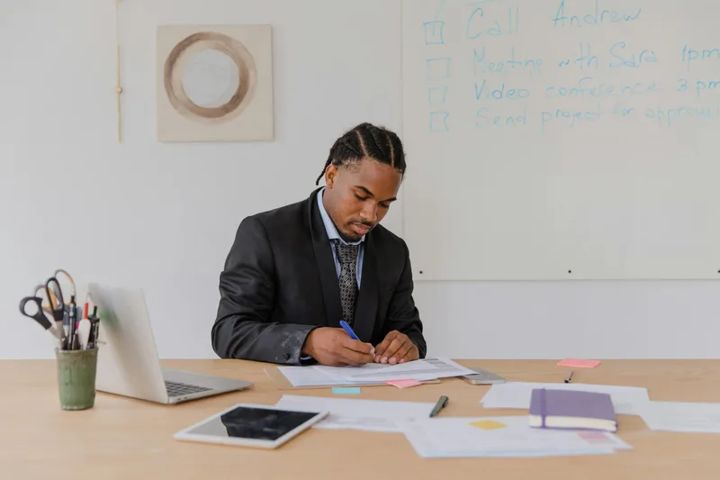 A professional reviewing documents at their desk with focused attention, working through a deliberate process