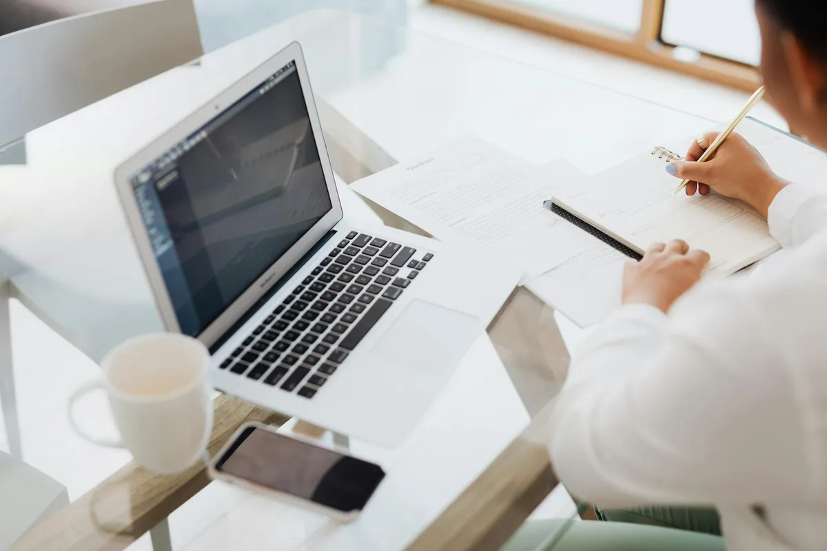 Solo creator reviewing platform options on a laptop with a notebook and coffee on the desk