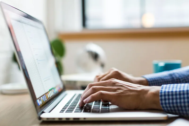 Close-up of person typing on a laptop, managing email marketing and automation