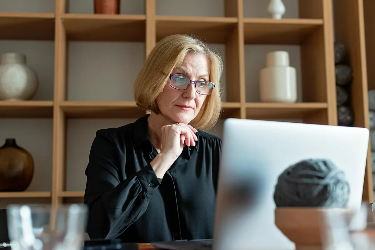 Person at a laptop in a focused home office, preparing a webinar presentation with notes on the desk
