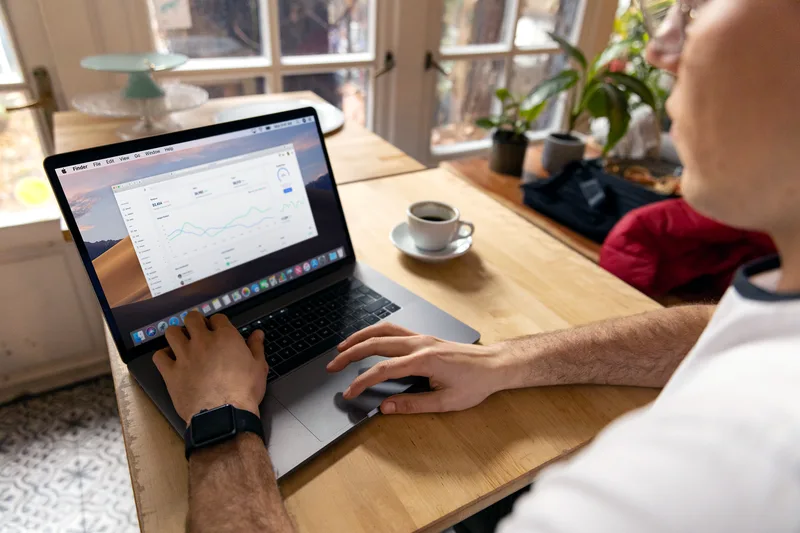 Solo creator at a laptop reviewing email analytics showing open rate, click rate, and opt-in metrics to identify which stage of their sales funnel is underperforming