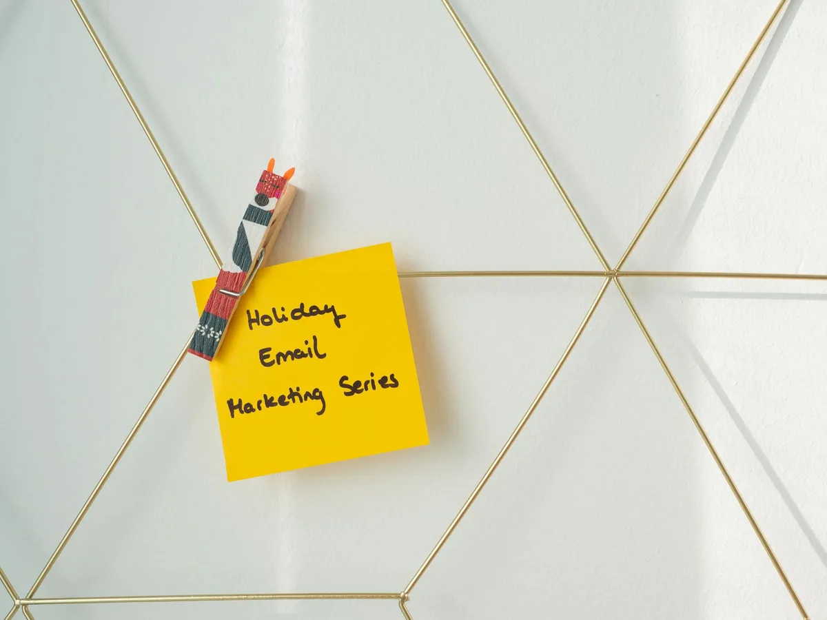 Sticky note with “email marketing” written on it against a coral background, representing the decision to choose an email tool for a creator business