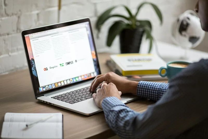 A person working on a laptop at a desk with coffee, managing email sequences for a solo creator business