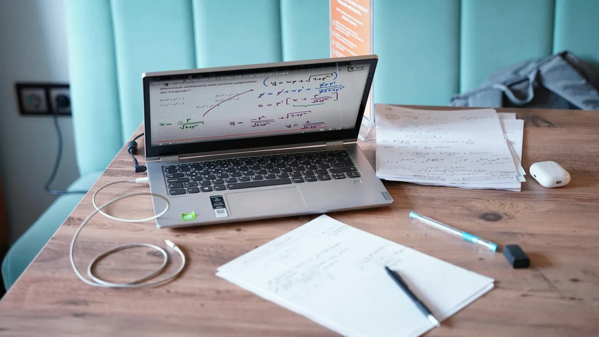 Solo creator workspace with laptop and notes, evaluating Kajabi alternatives against a funnel framework