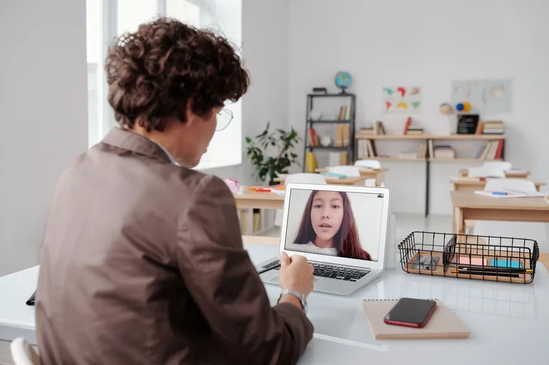 Teacher conducting an online class from a classroom using a laptop, focused on interactive learning